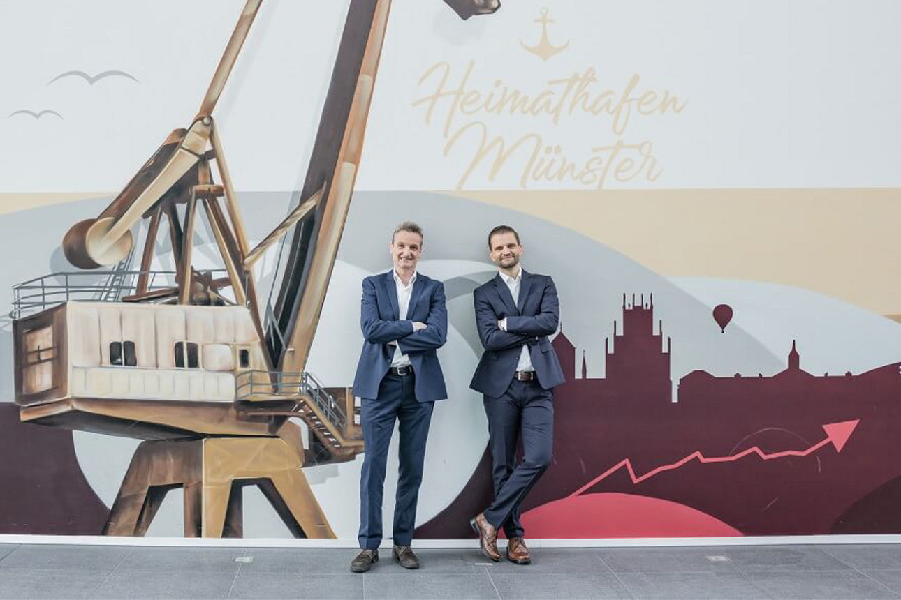 Vorstand steht vor dem Graffiti-Bild vom Hafen.