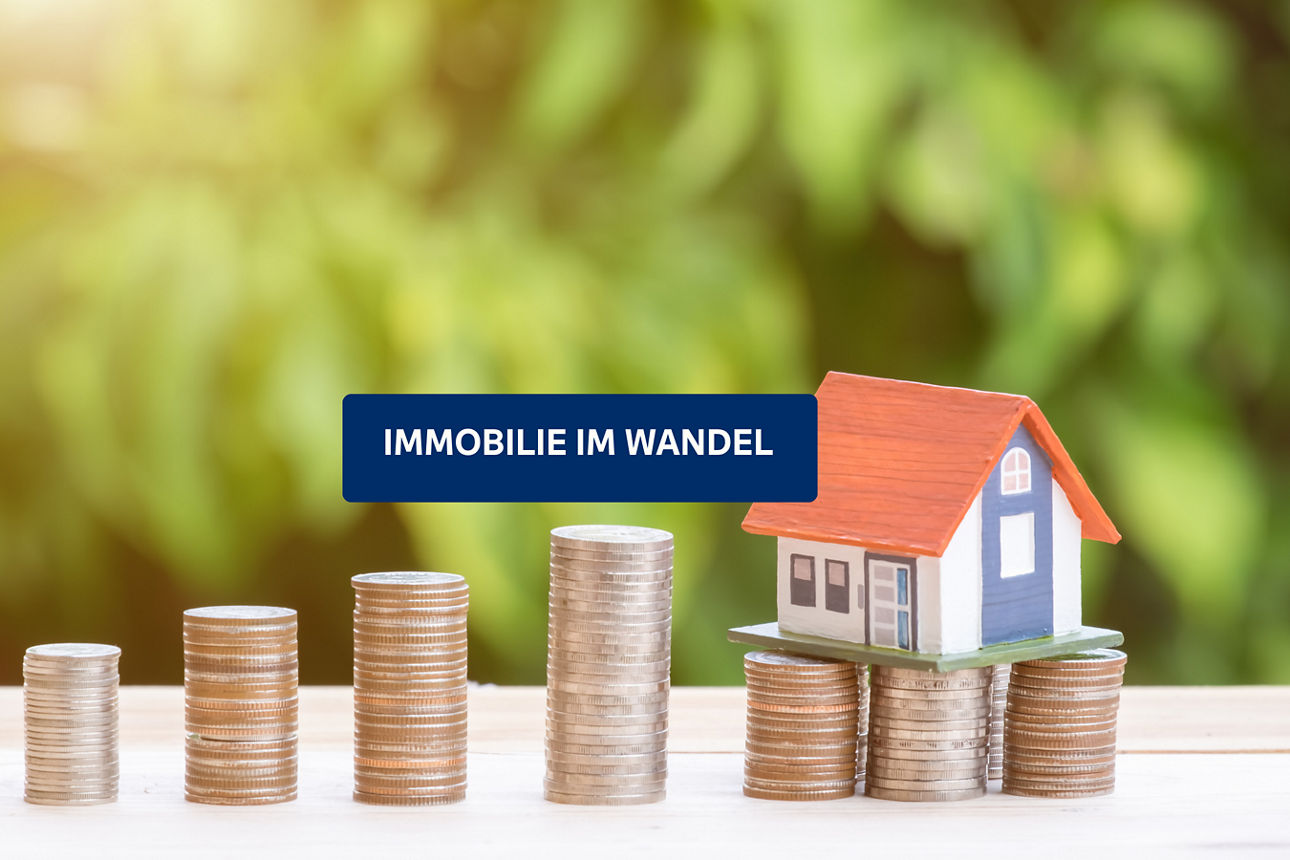 Ansteigende Münzstapel tragen ein Modellhaus. Text: „Immobilie im Wandel“.