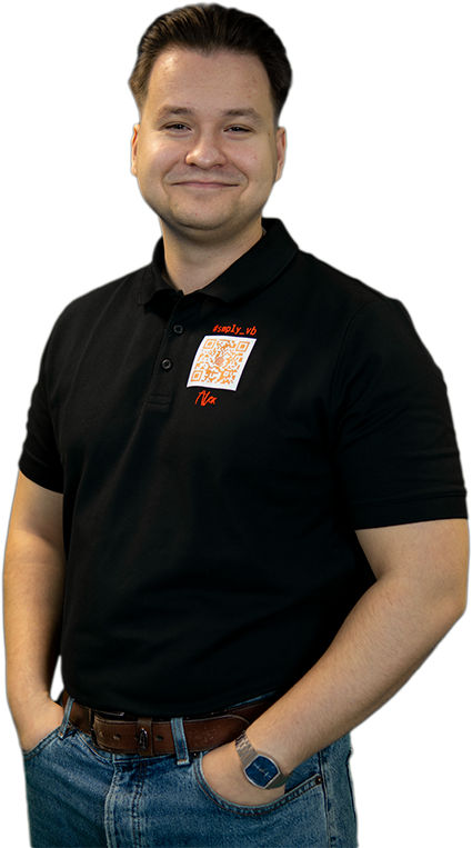 Junger Berufstätiger in einem schwarzen Poloshirt, hellen Jeans und einer Armbanduhr.