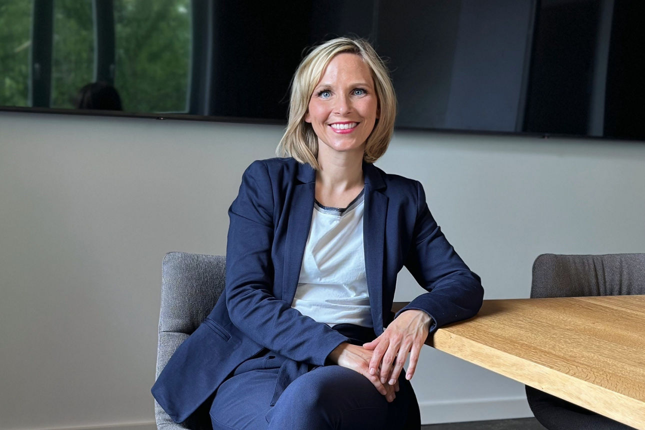 Ein junger Mann sitzt lächelnd am Schreibtisch