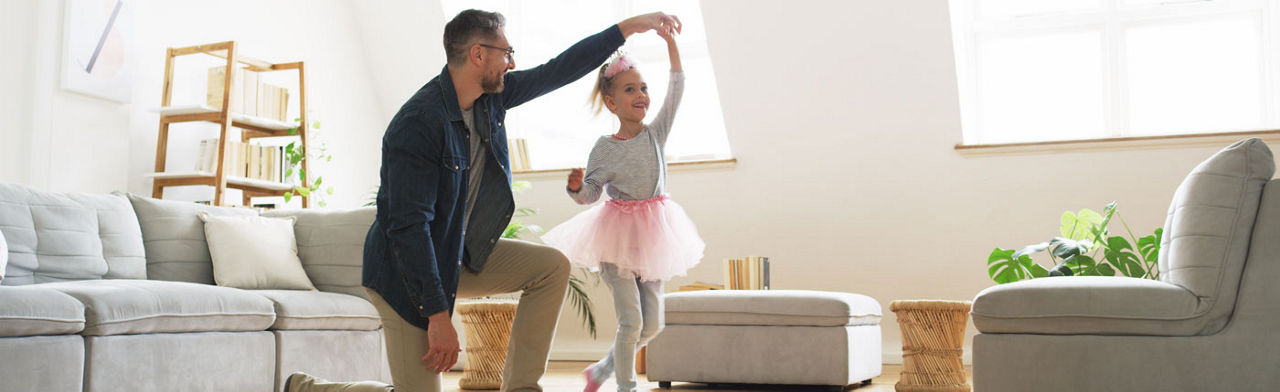 Ein Vater tanzt mit seiner Tochter im Wohnzimmer