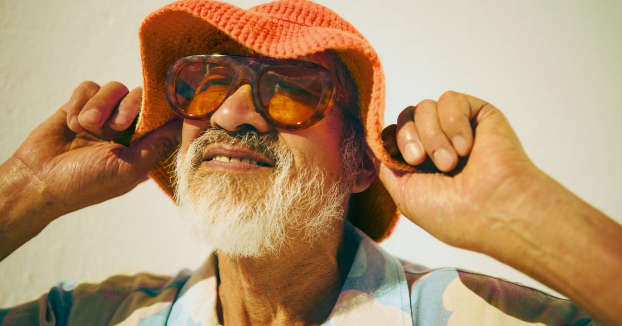 Mann mit gestricktem orangenen Hut und Sonnenbrille ist gelassen.