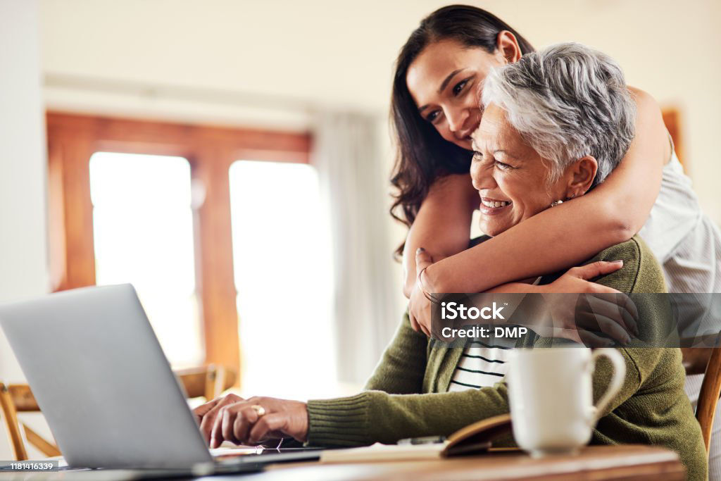 Cropped shot of an attractive young woman hugging her grandmother before helping her with her finances on a laptop
