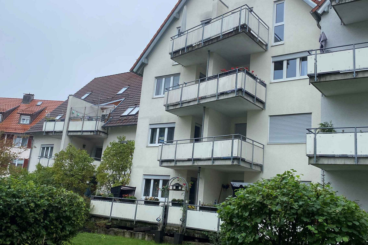 Ein Mehrfamilienhaus in der Außenansicht. Es sind drei Balkone zu sehen.