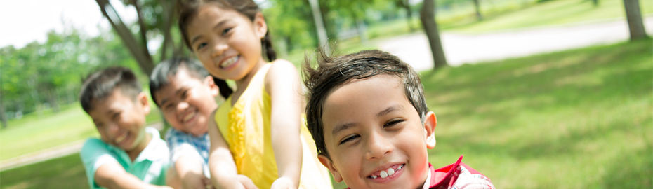Die Kinder spielen Tauziehen auf einer Wiese