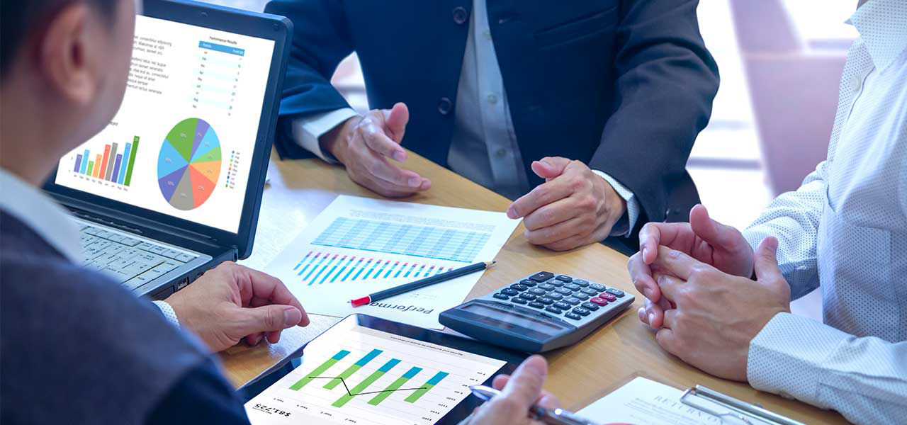Das Analysegespräch: Geschäftsmänner mit Rechner und Charts auf dem Bürotisch