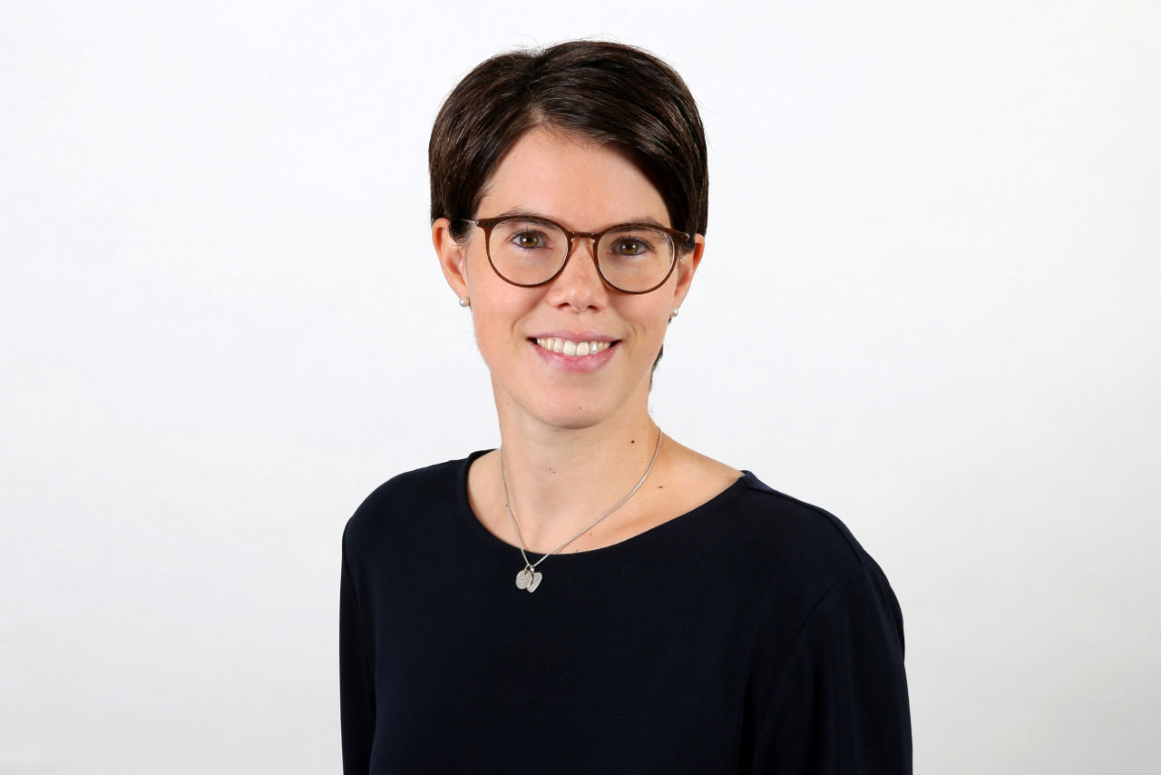 Ein lächelnder Frau schaut in die Kamera.