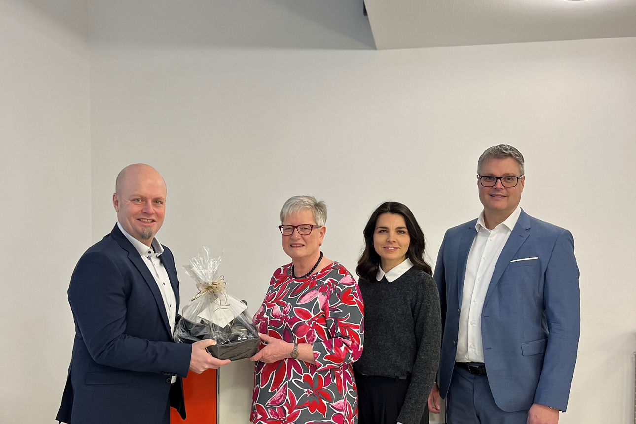 Das Bild zeigt vier Personen, zwei Männer und zwei Frauen, die in einem modernen Raum stehen.