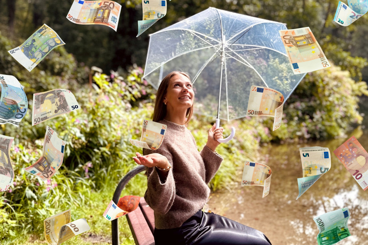Frau mit Regenschirm und geöffneter Hand am See mit verschiedenen Euroscheinen die einen Regen bilden.