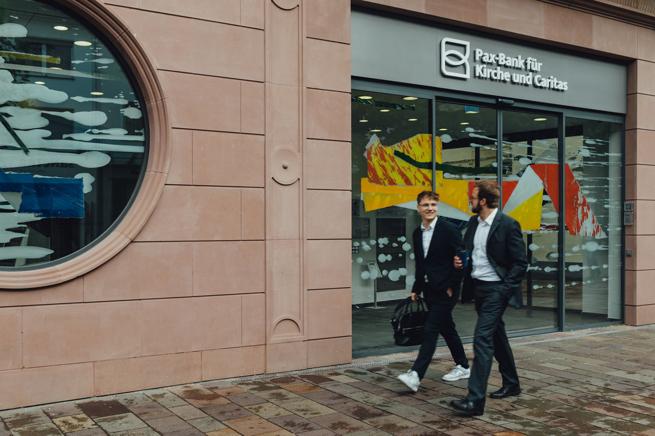 Zwei Mitarbeitende laufen vor der Filiale Paderborn entlang