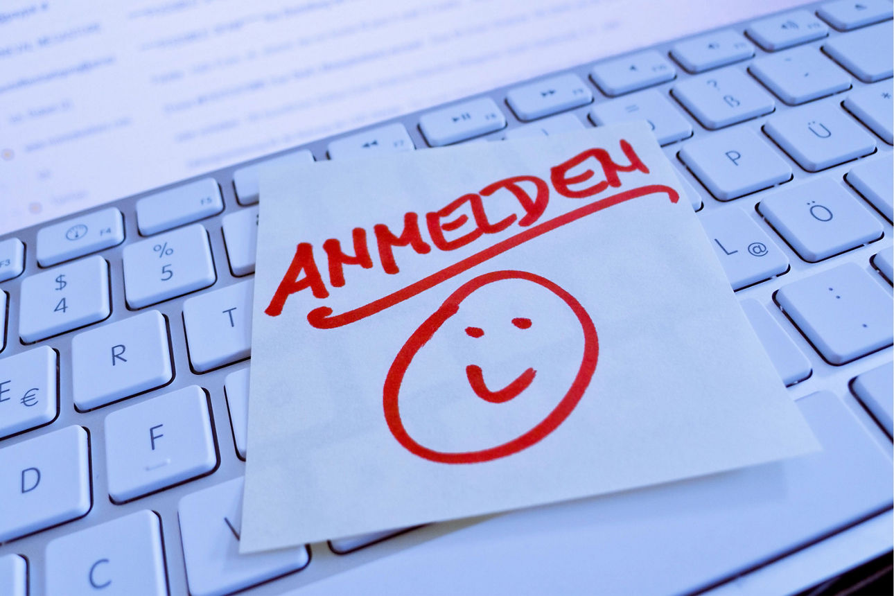 Ein Zettel mit dem Schriftzug „Anmelden“ liegt auf einer Tastatur