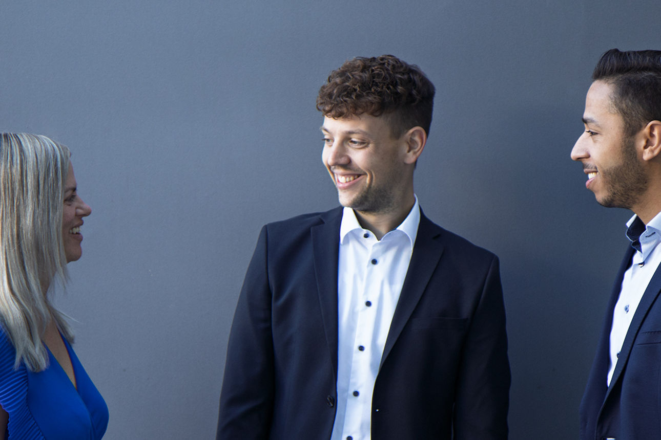 Zwei Männer und eine Frau lächeln und unterhalten sich