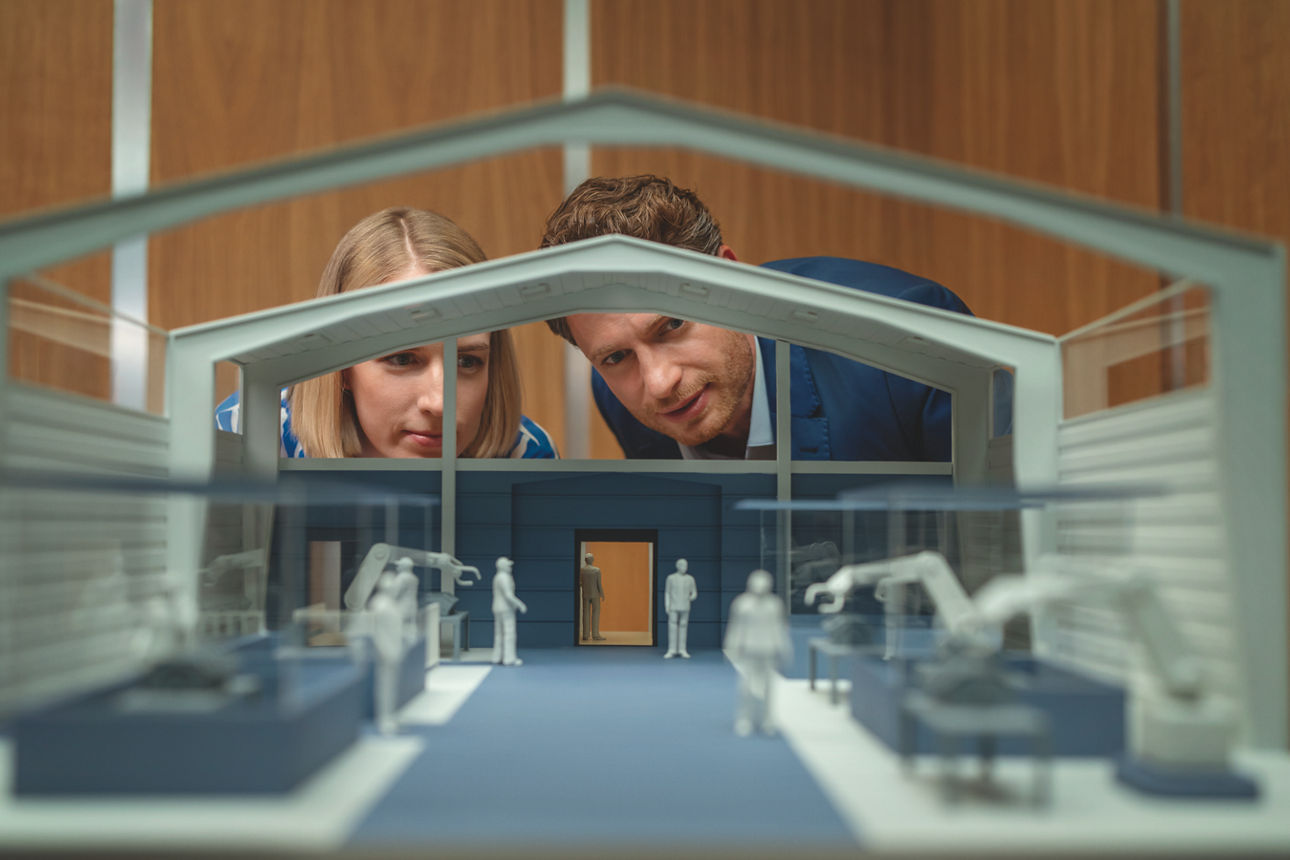 Berater mit Kundin vor dem Modell einer Halle