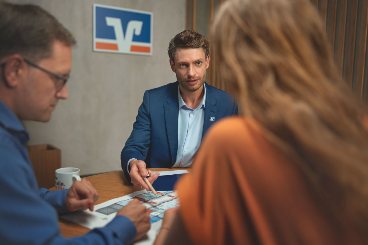 Berater am Tisch mit Kundin und Kunde