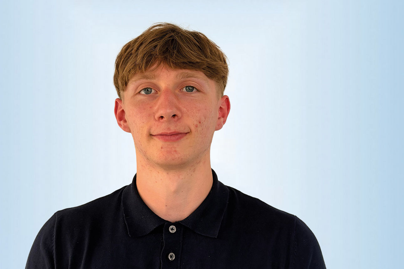 Praktikant Anton Skowronnek vor einem blauen Hintergrund 