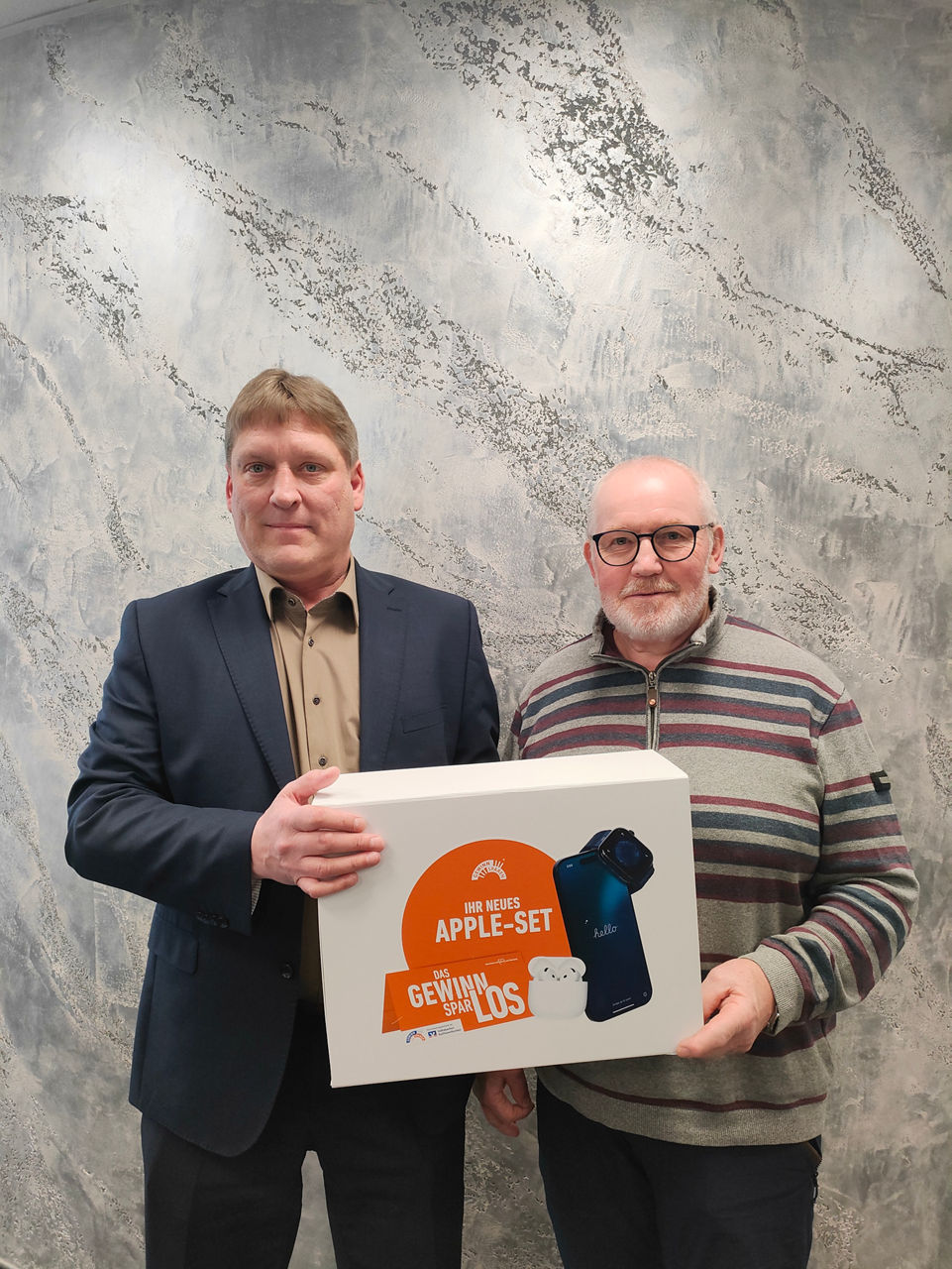 Kundenbetreuer Bernd Lutz übergibt ein Apple-Set an seinen Kunden