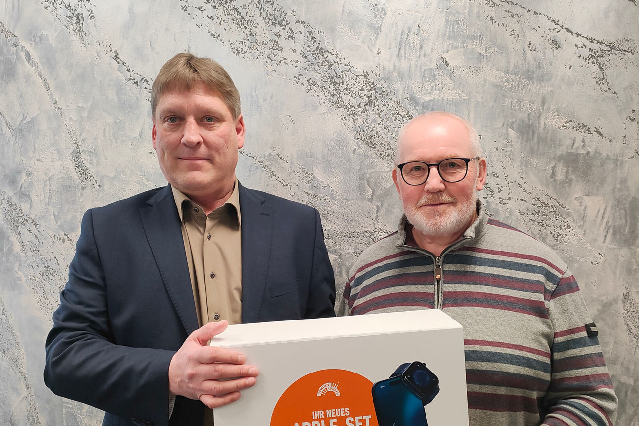 Kundenbetreuer Bernd Lutz übergibt ein Apple-Set vom Gewinnsparen an seinen Kunden