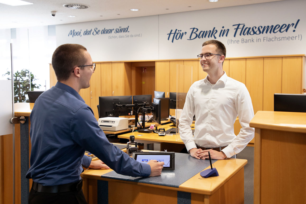 Männer sitzten lächelnd am Schreibtisch in der Bank