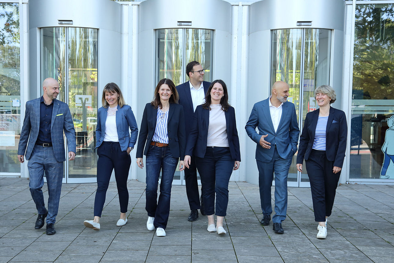 Lachende Menschen in Businesskleidung gehen gemeinsam von einem Gebäude weg