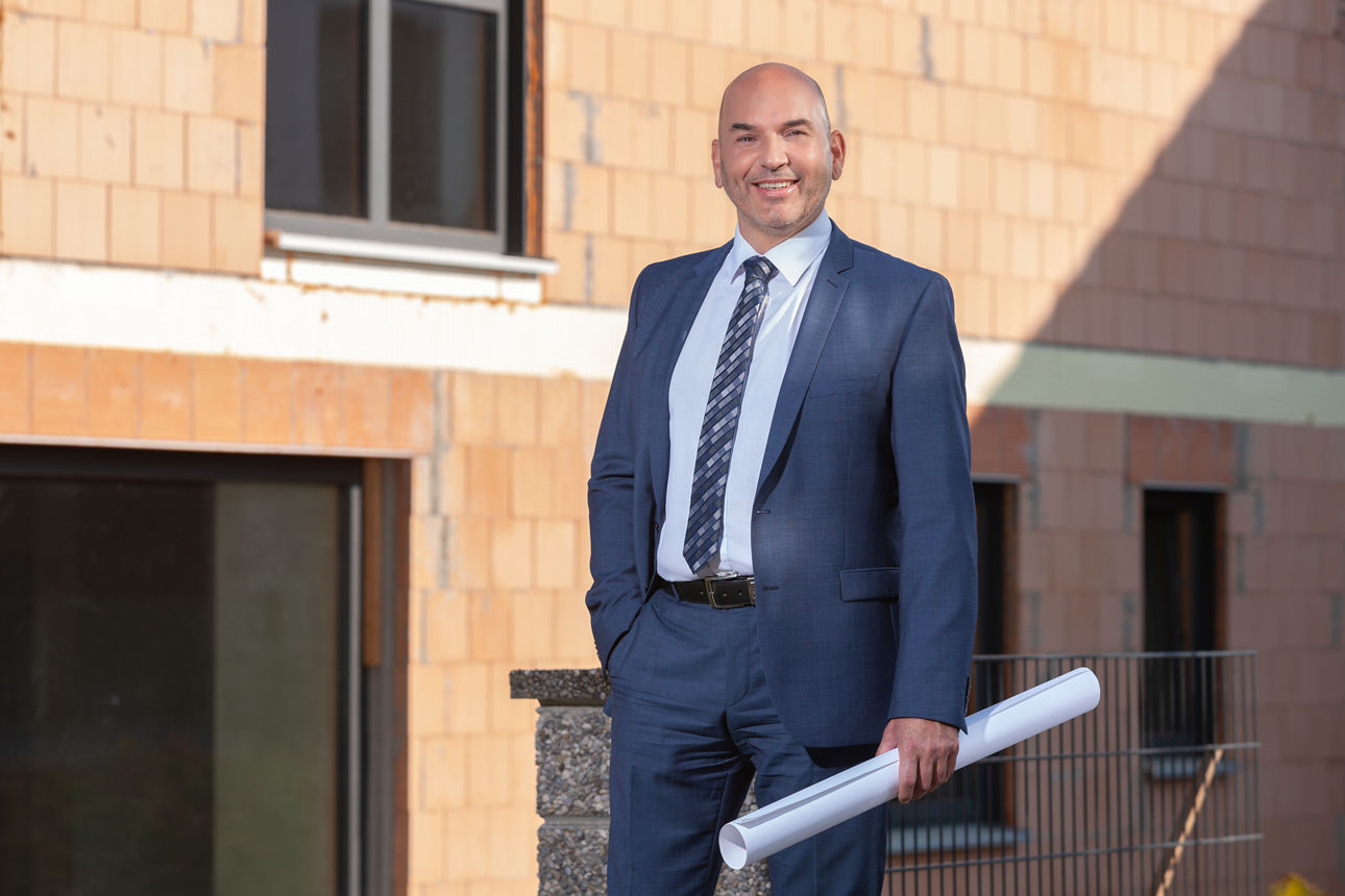 Mann im Anzug vor Rohbau