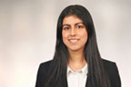 Neha Asghar hat schwarze lange Haare und trägt ein Businessoutfit