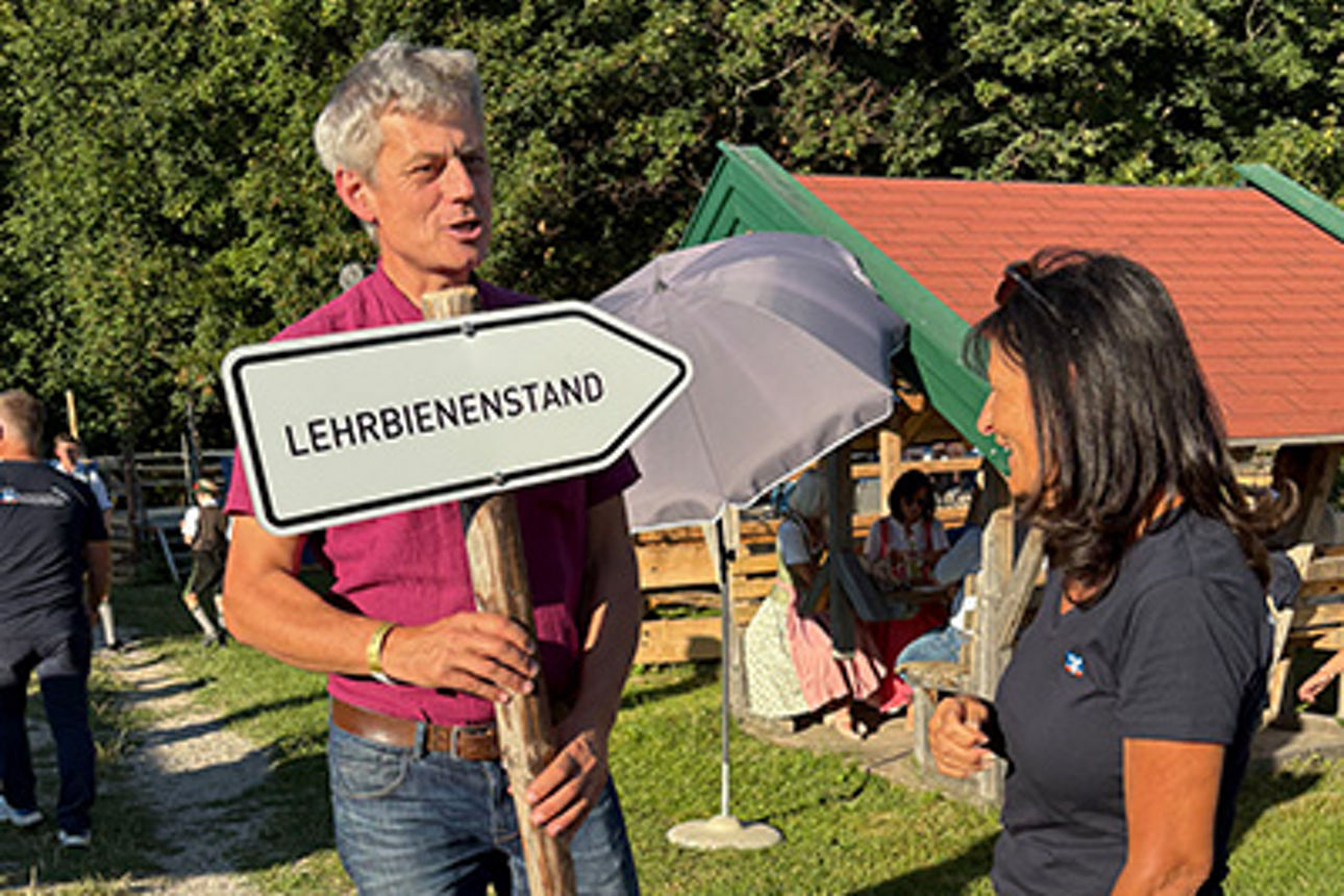 Ein Mann hält ein Schild und spricht mit einer Frau.