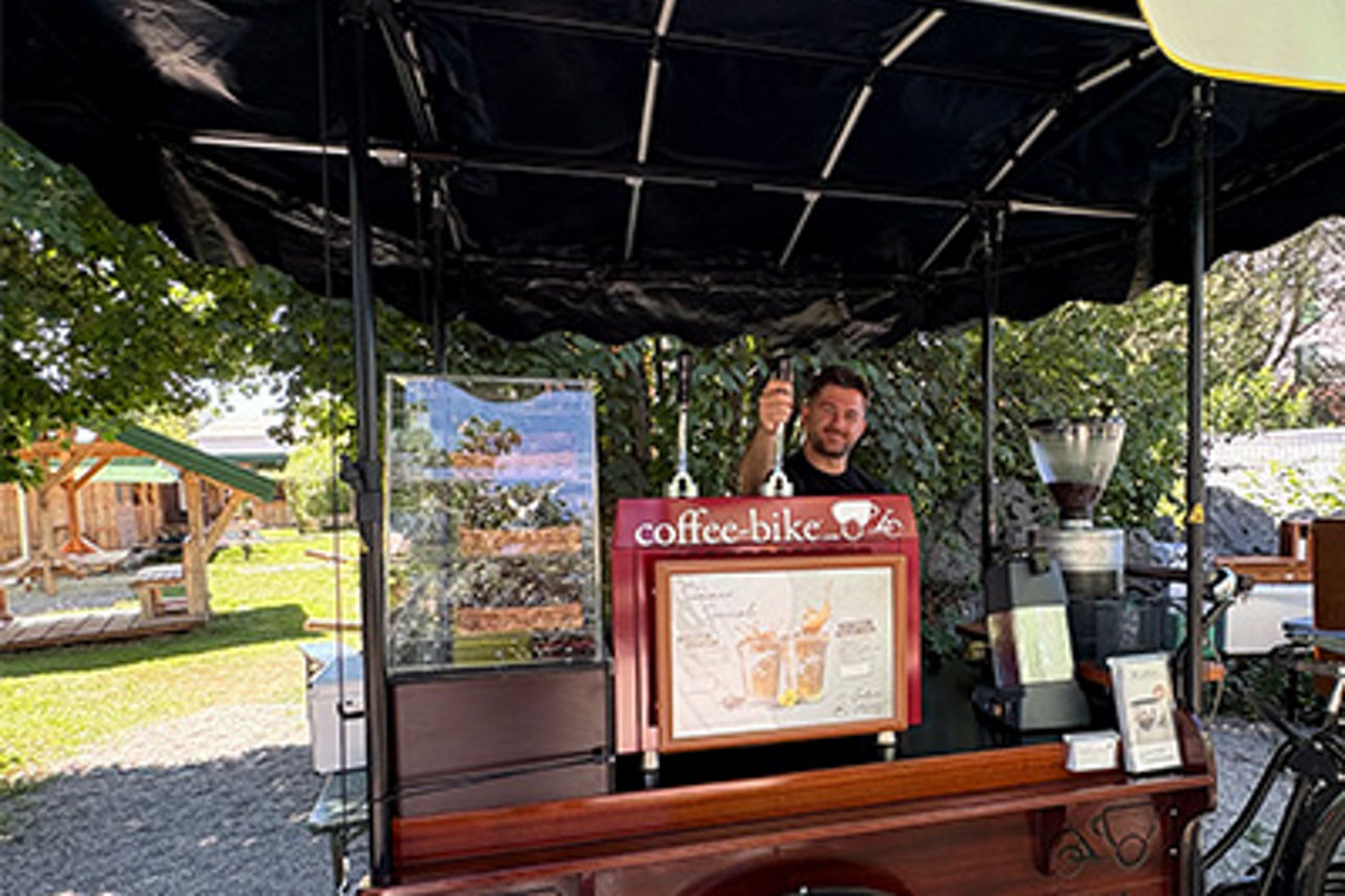 Ein Mann steht an einem Coffeebike und verteilt Kaffee.