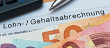 Geldscheine liegen auf einem Papier. Auf diesem ist das Wort "Gehaltsabrechnung" zu lesen