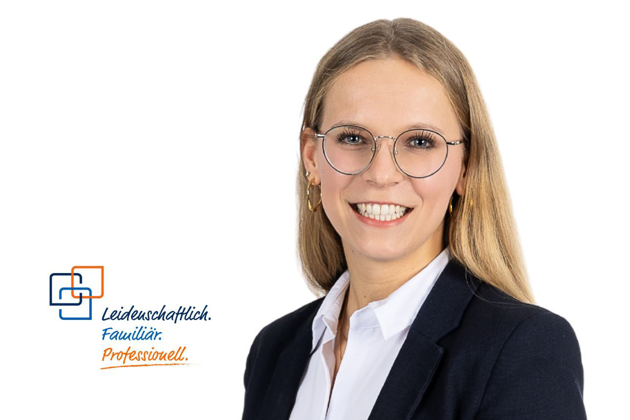 Frau mit Brille und Blazer, lächelnd, vor weißem Hintergrund