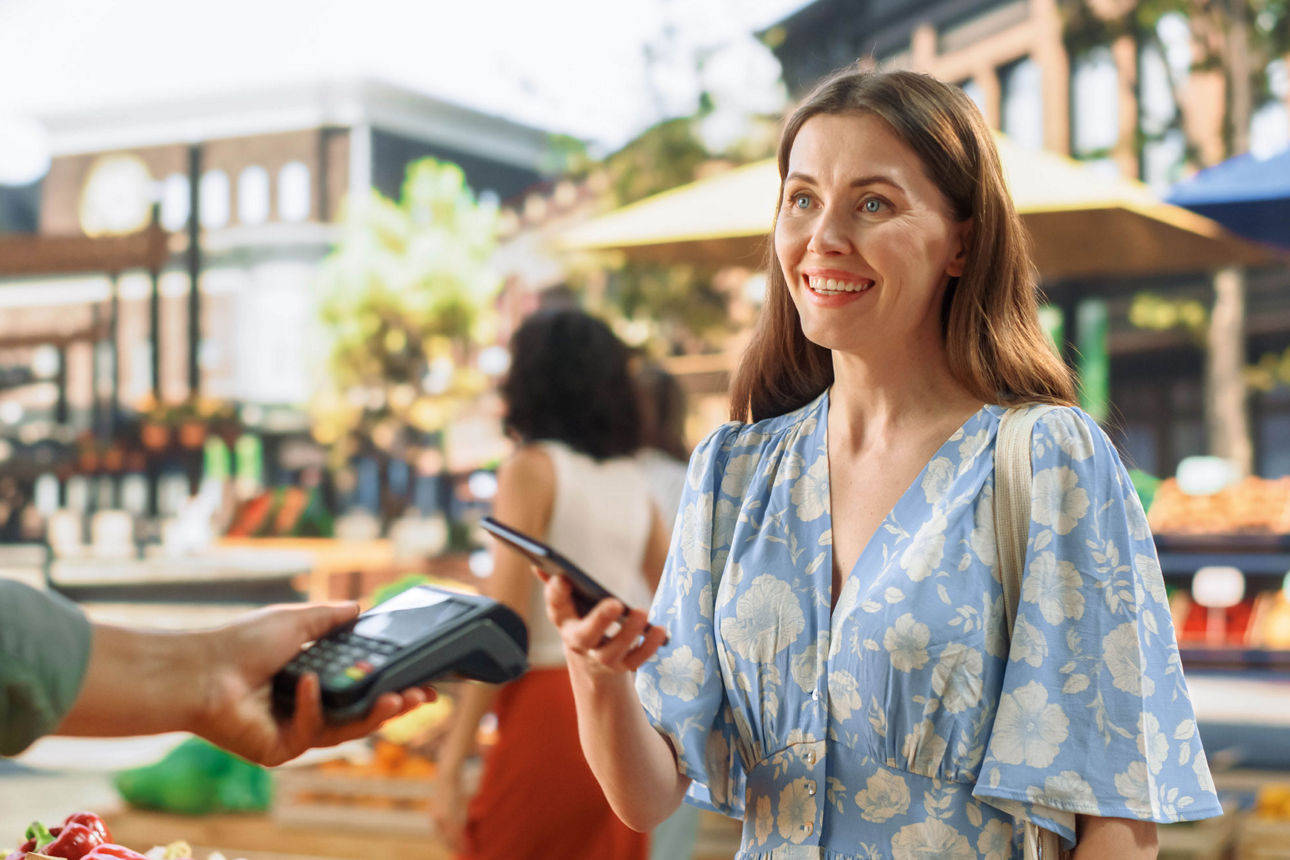 Lächelnde junge Frau bezahlt mit Handy