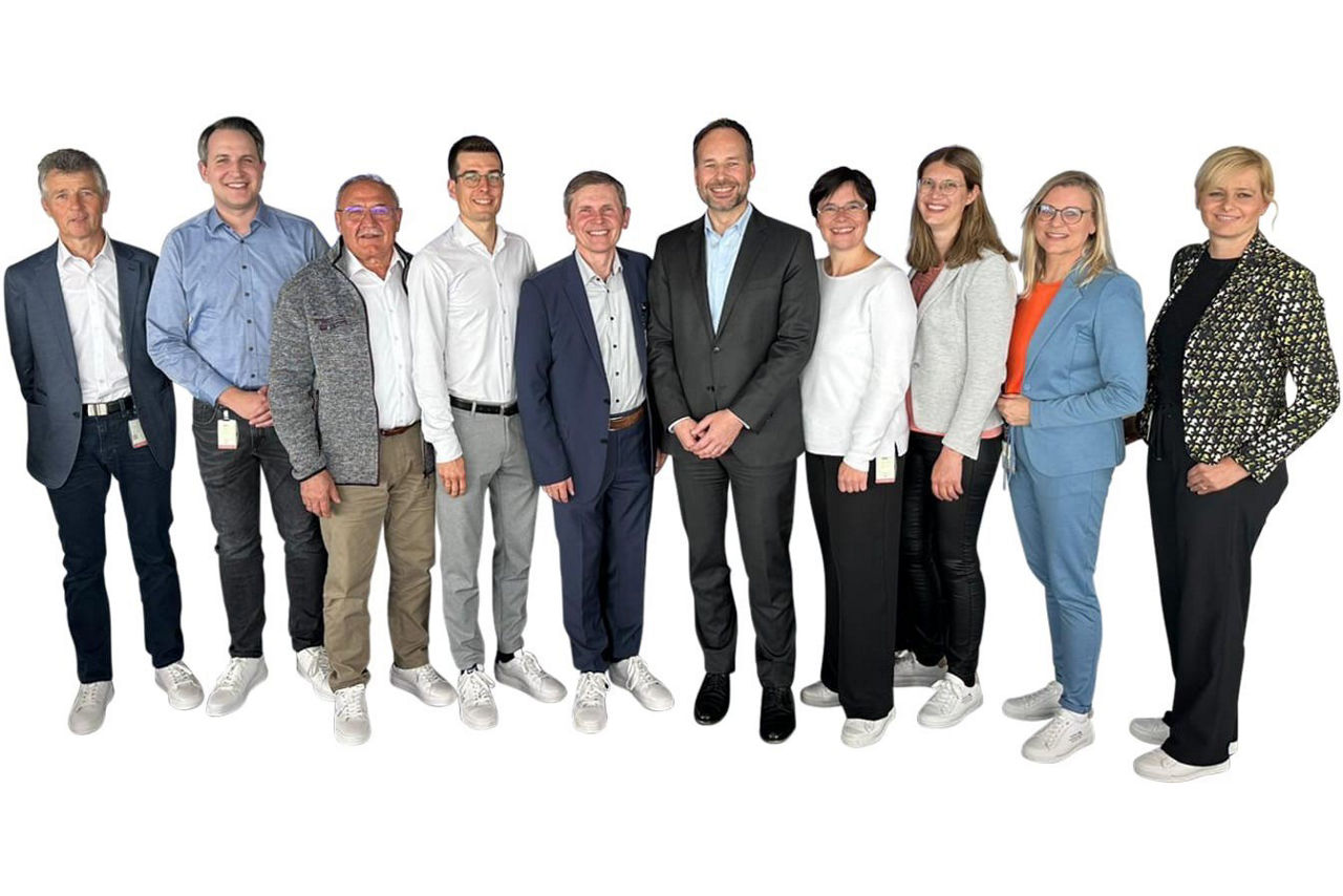 Gruppenbild mit zehn Personen, alle schauen freundlich in die Kamera.