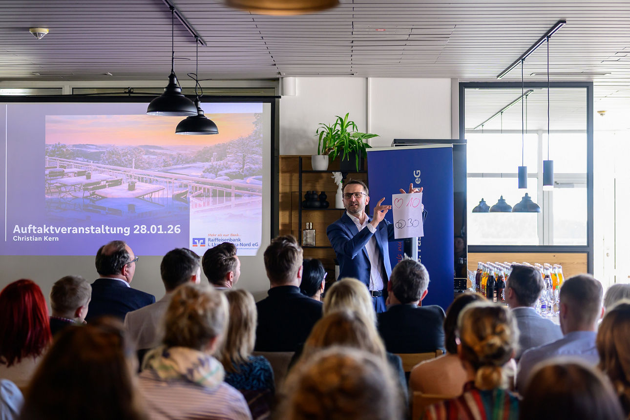 Referent spricht vor Publikum bei Informationsveranstaltung mit Präsentation im modernen Raum