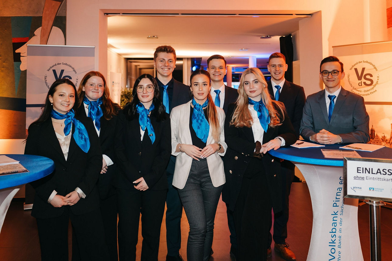 Auszubildende bei Veranstaltung, 9 Personen in elegantem Business-Outfit posieren für ein Foto auf einer Veranstaltung