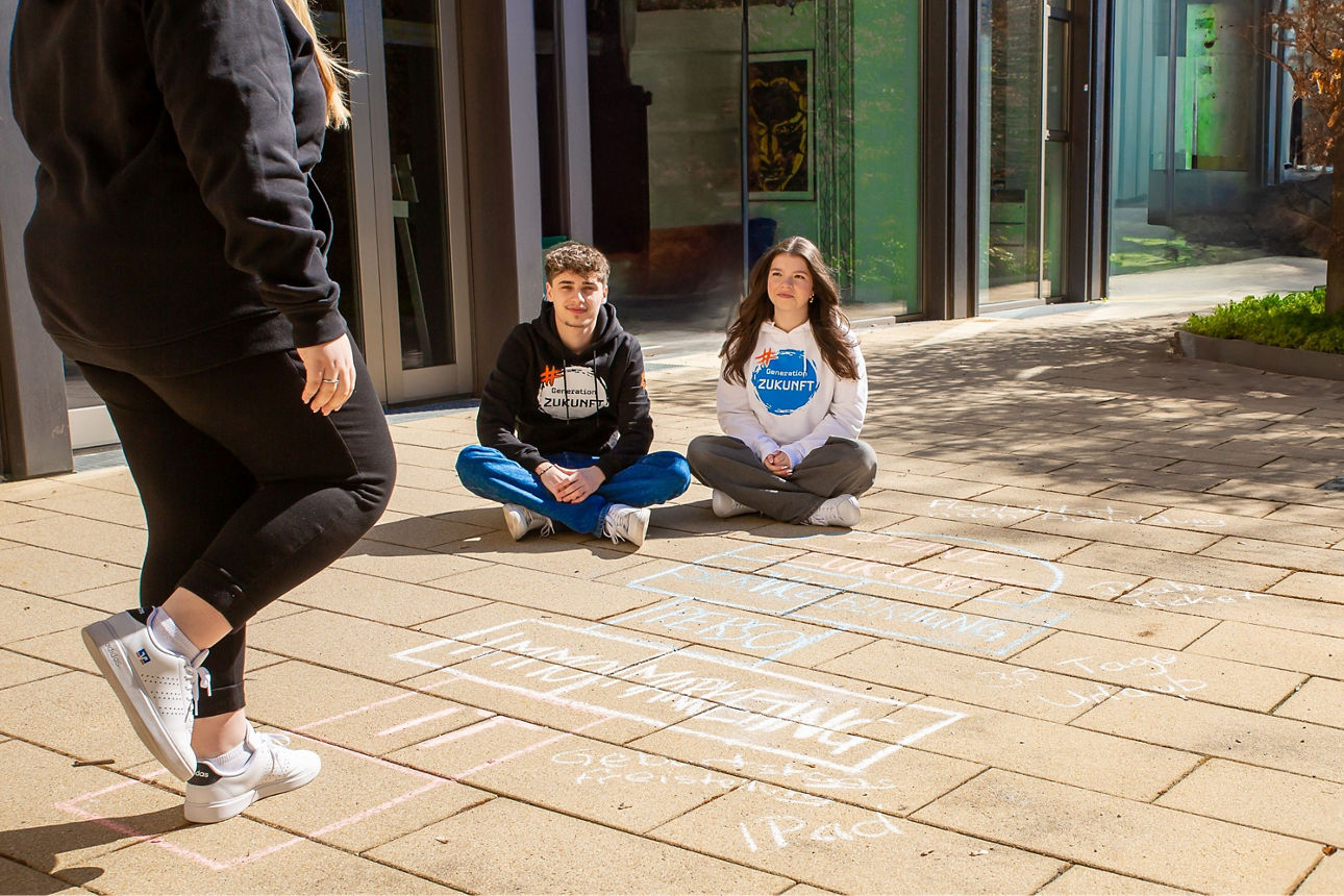 Drei junge Menschen spielen ein Straßenspiel
