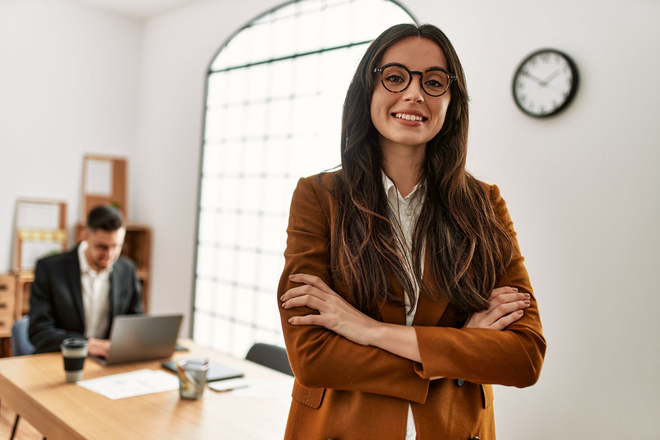 Junge Dame mit langen braunen Haaren im Büro lächelnd