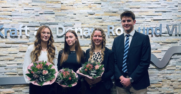 Vier Absolventen mit Blumensträußen