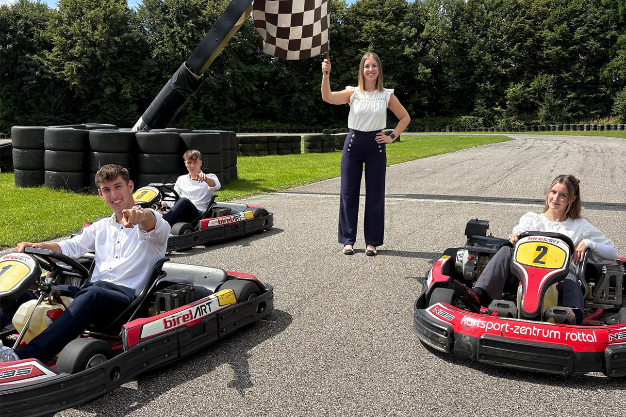 Junge Menschen sitzen in Kartautos auf einer Rennstrecke