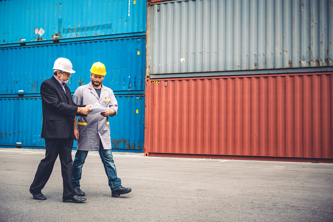Zwei Männer laufen vor Containern am Hafen