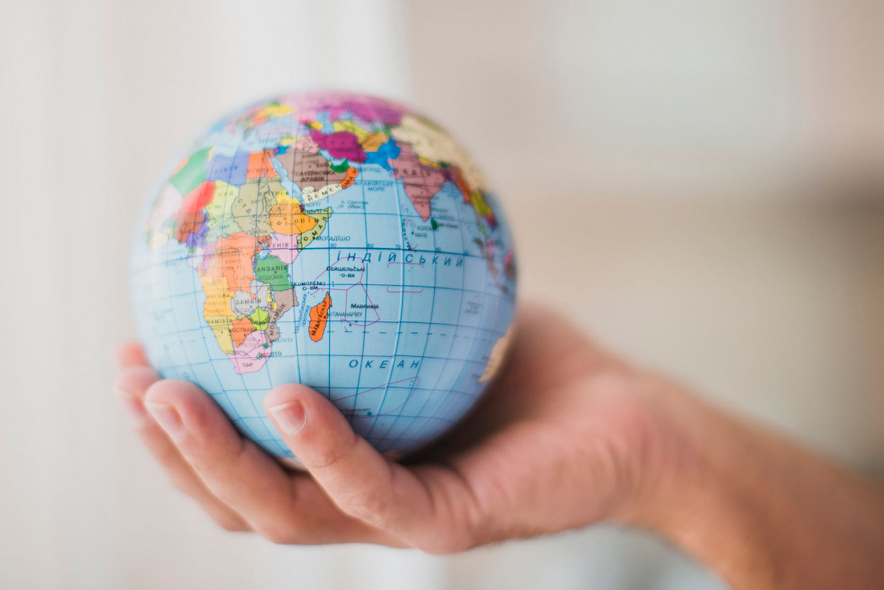 In einer Hand wird ein Globus gehalten