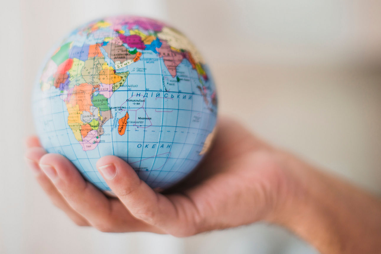 In einer Hand wird ein Globus gehalten