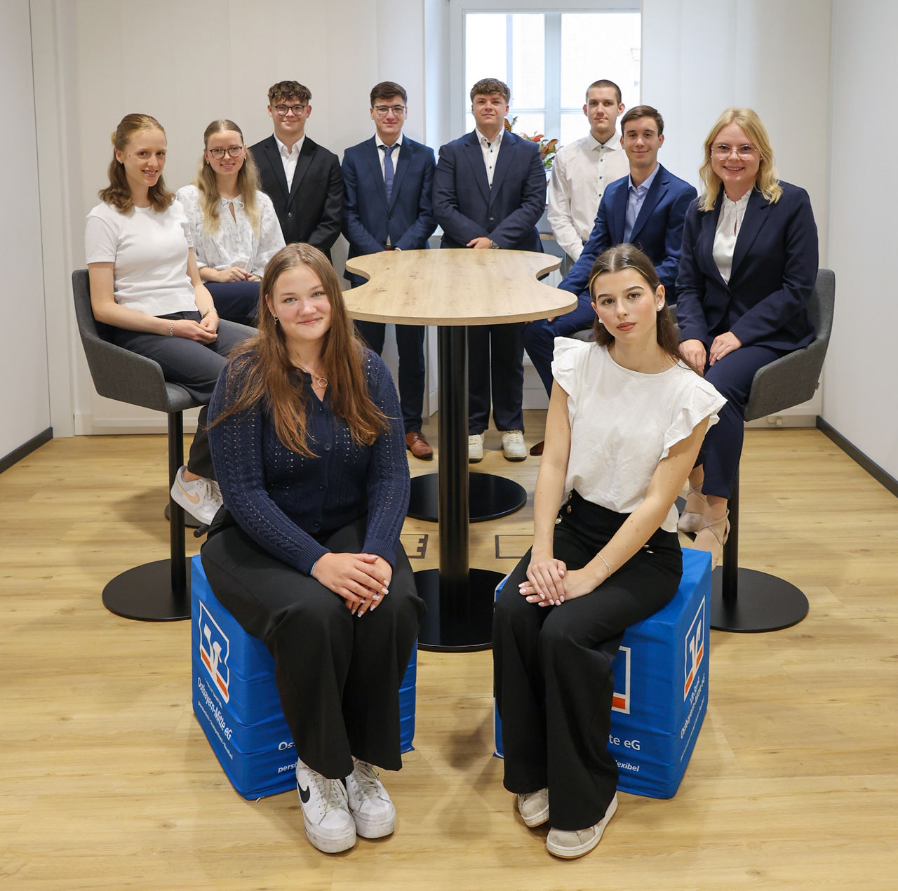 Gruppenfoto von zehn jungen Menschen in Businesskleidung in einem modernen Büro.