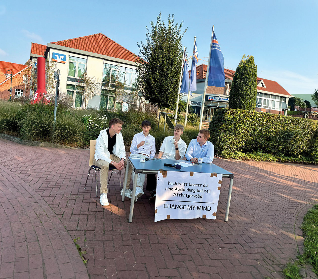 Auszubildende sitzen vor der Bank an einem Tisch