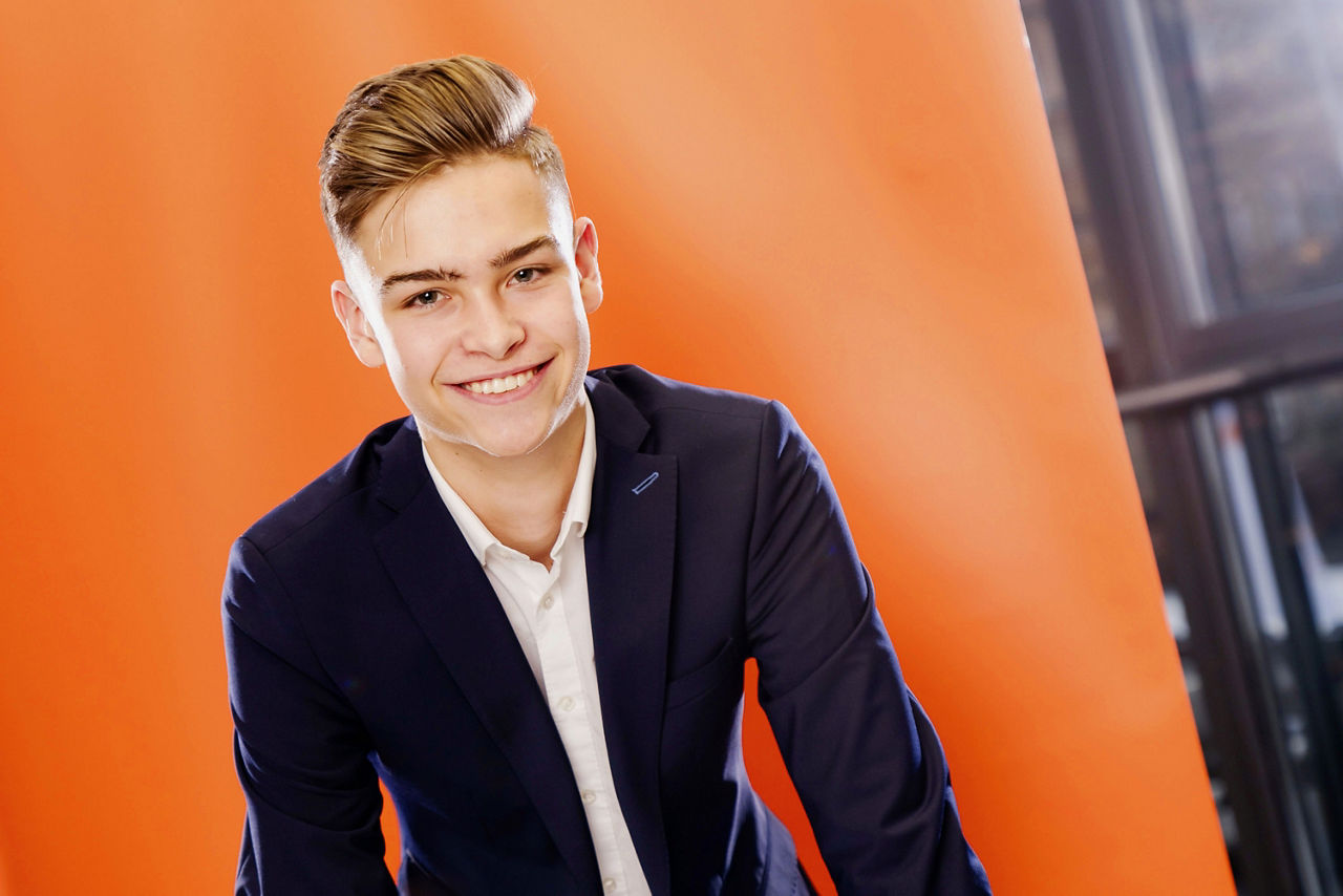 Auszubildender vor orangefarbenem Rollup