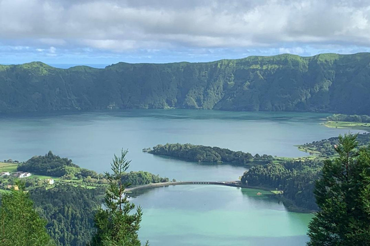 Ein blauer Kratersee umgeben von grün bewachsenen Bergen