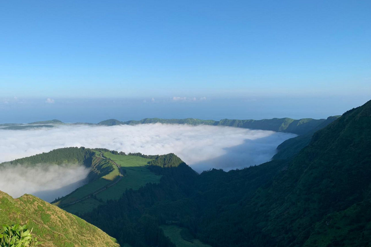 Blick auf eine grüne Vulkanlandschaft und im Krater sind Wolken