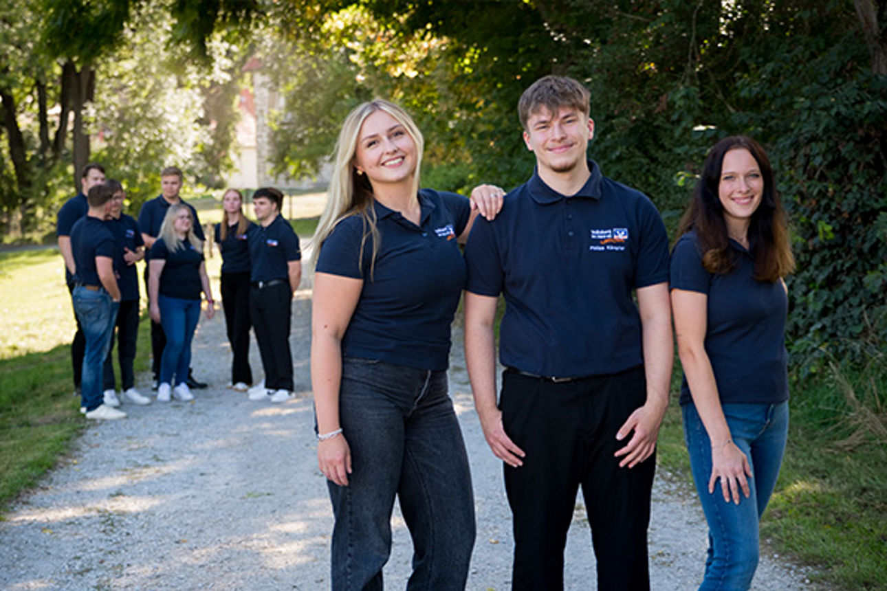3 Azubis im Vordergrund und mehrere im Hintergrund