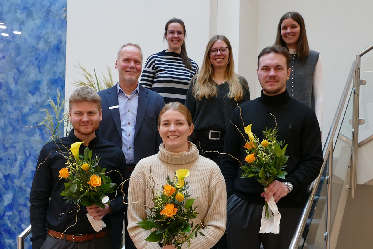 Sieben Menschen stehen lächelnd auf einer Treppe
