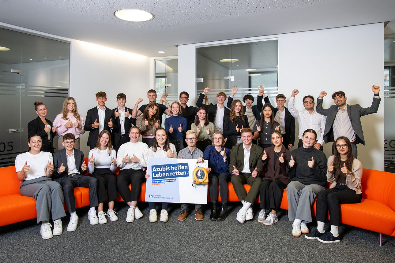 28 Azubis unser Bank präsentieren ihre Aktion "Azubis helfen Leben retten" - eine Person hält einen Defibrillator