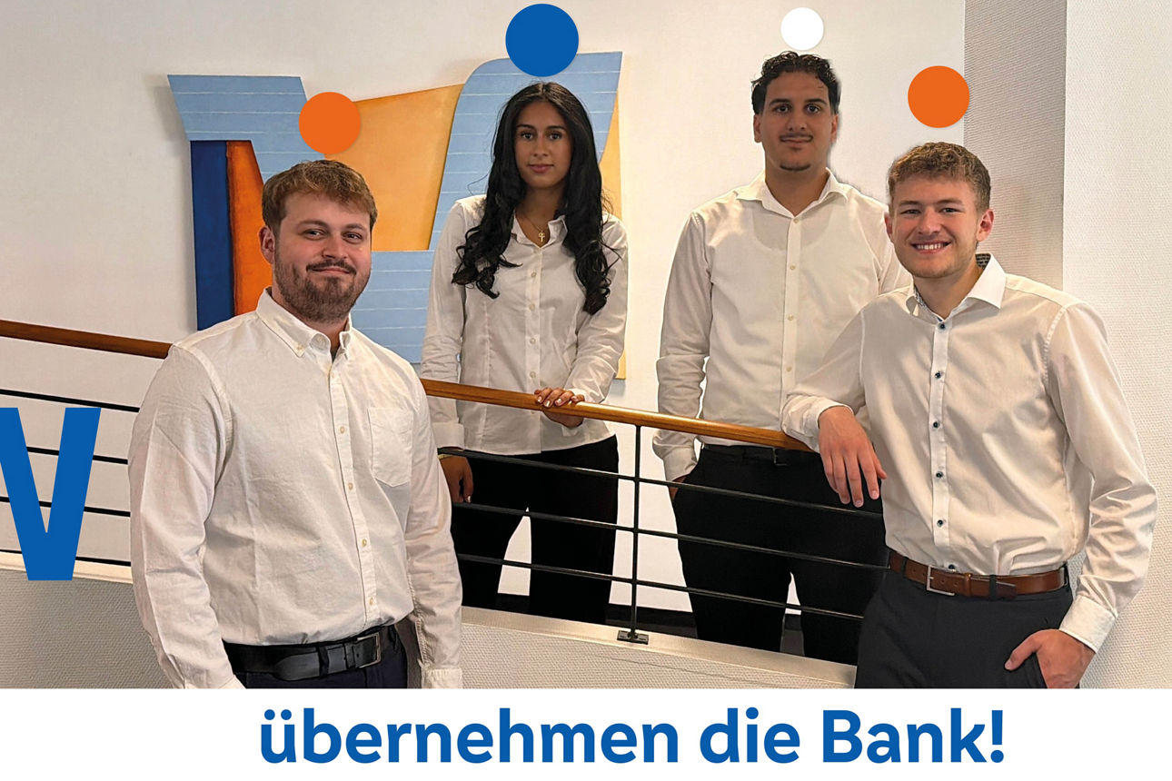 Eine Gruppe von vier jungen Berufstätigen in Geschäftskleidung, die auf einer Innentreppe stehen.