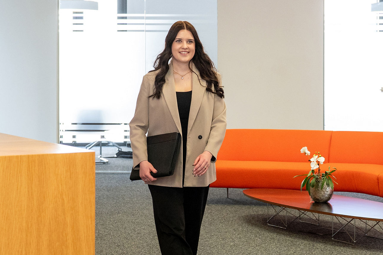 Auszubildende geht zielstrebig ihren Weg - im Hintergrund ist eine orange Couch zu sehen